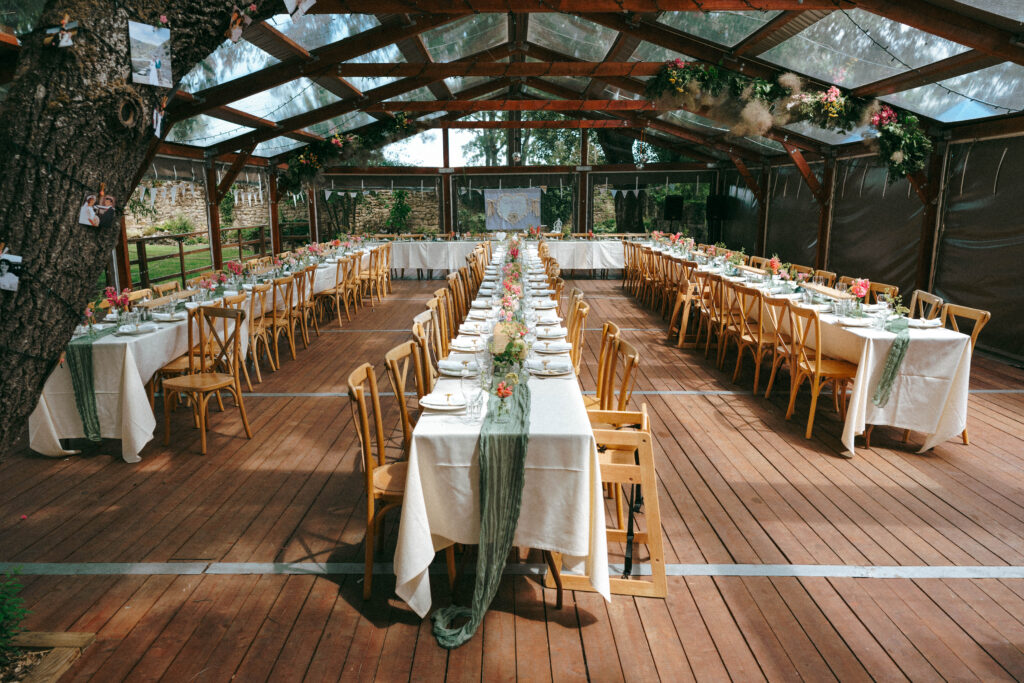 Long wedding reception tables set under a glass marquee roof