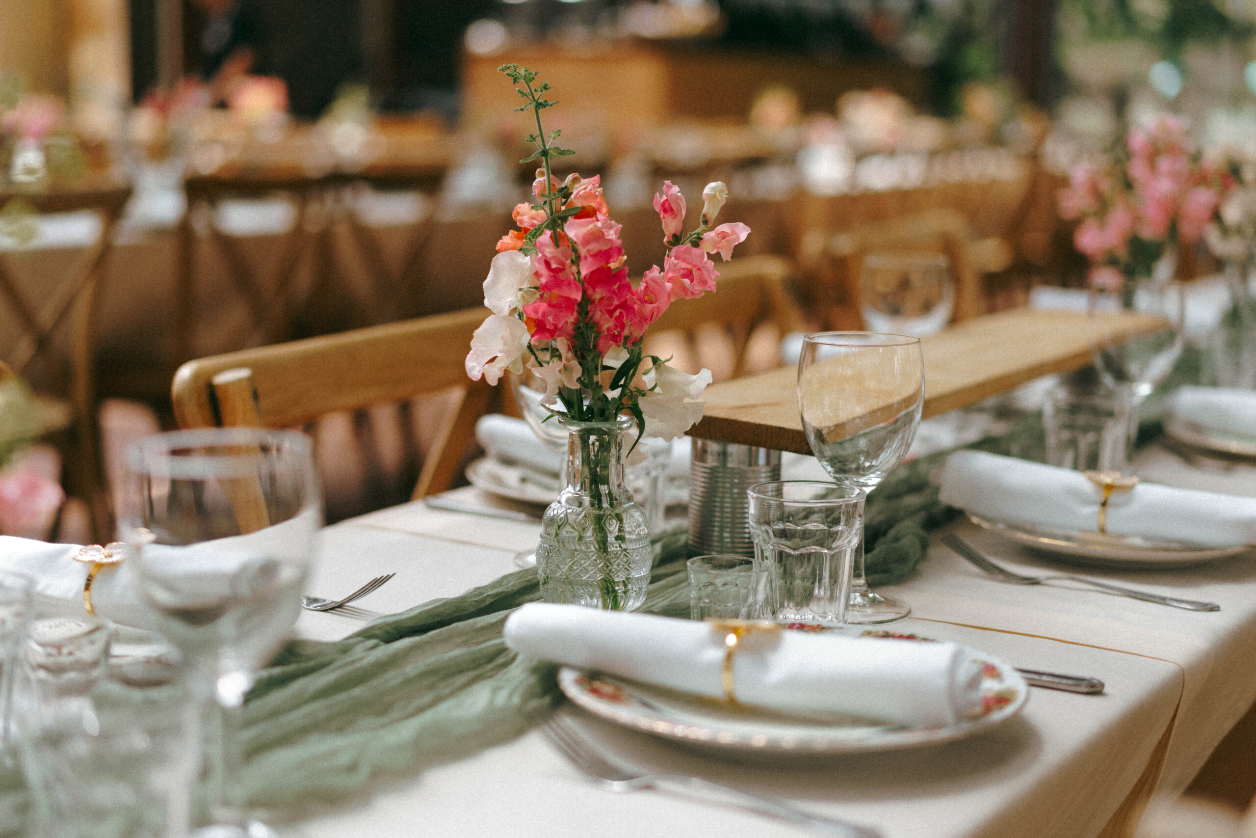 Wedding reception table setting with pink florals and greenery runner