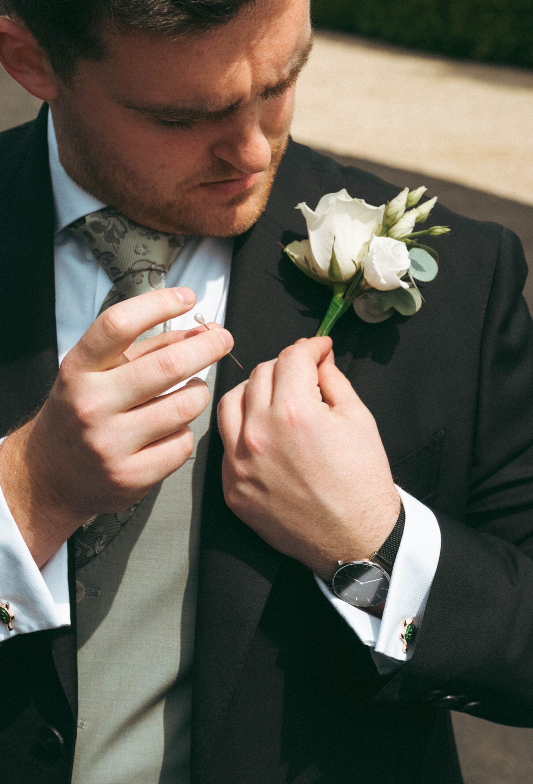 Groom having his buttonhole fixed on his wedding morning, an observational documentary wedding photograph
