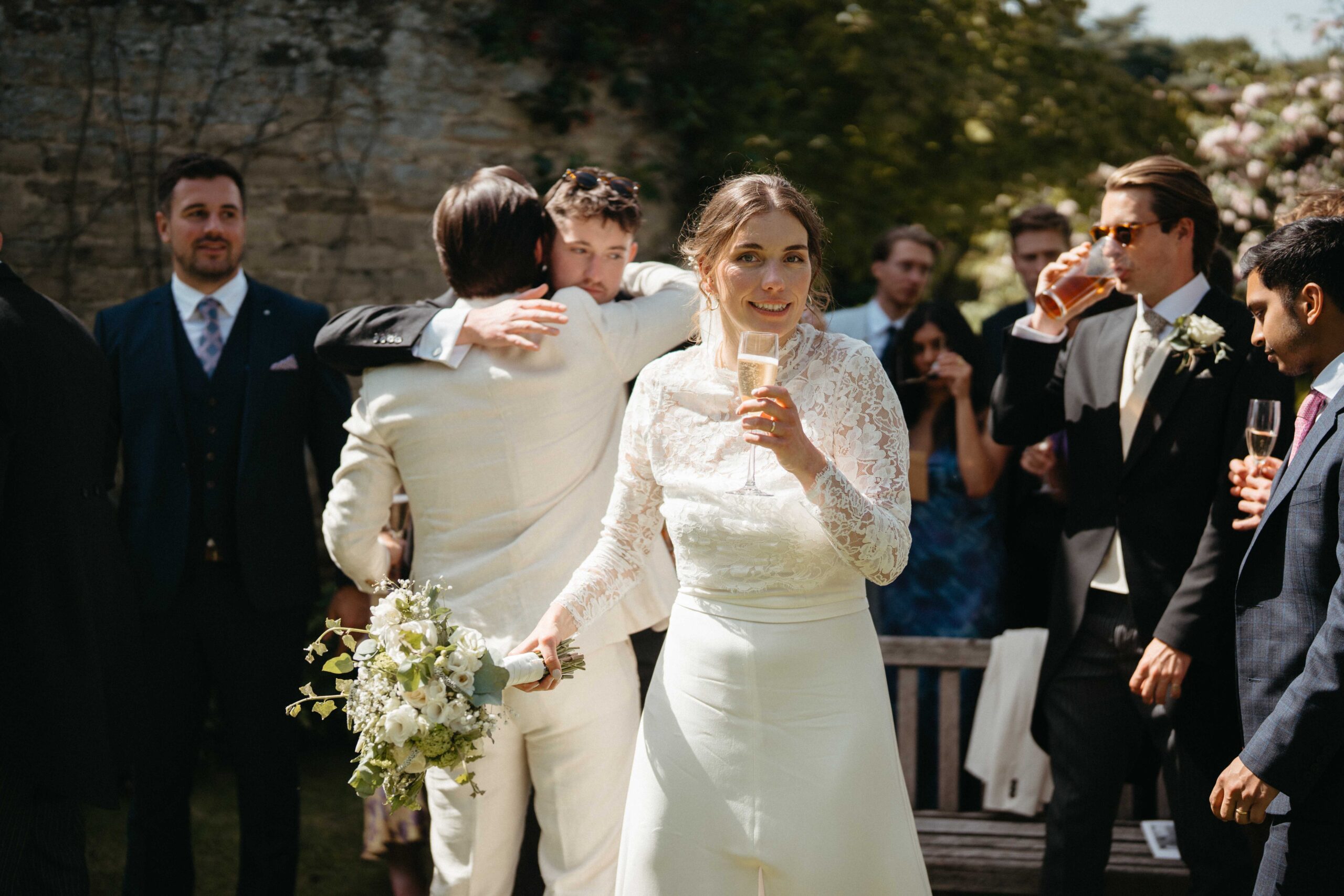 Bride toasting with champagne surrounded by guests at a Rousham House wedding
