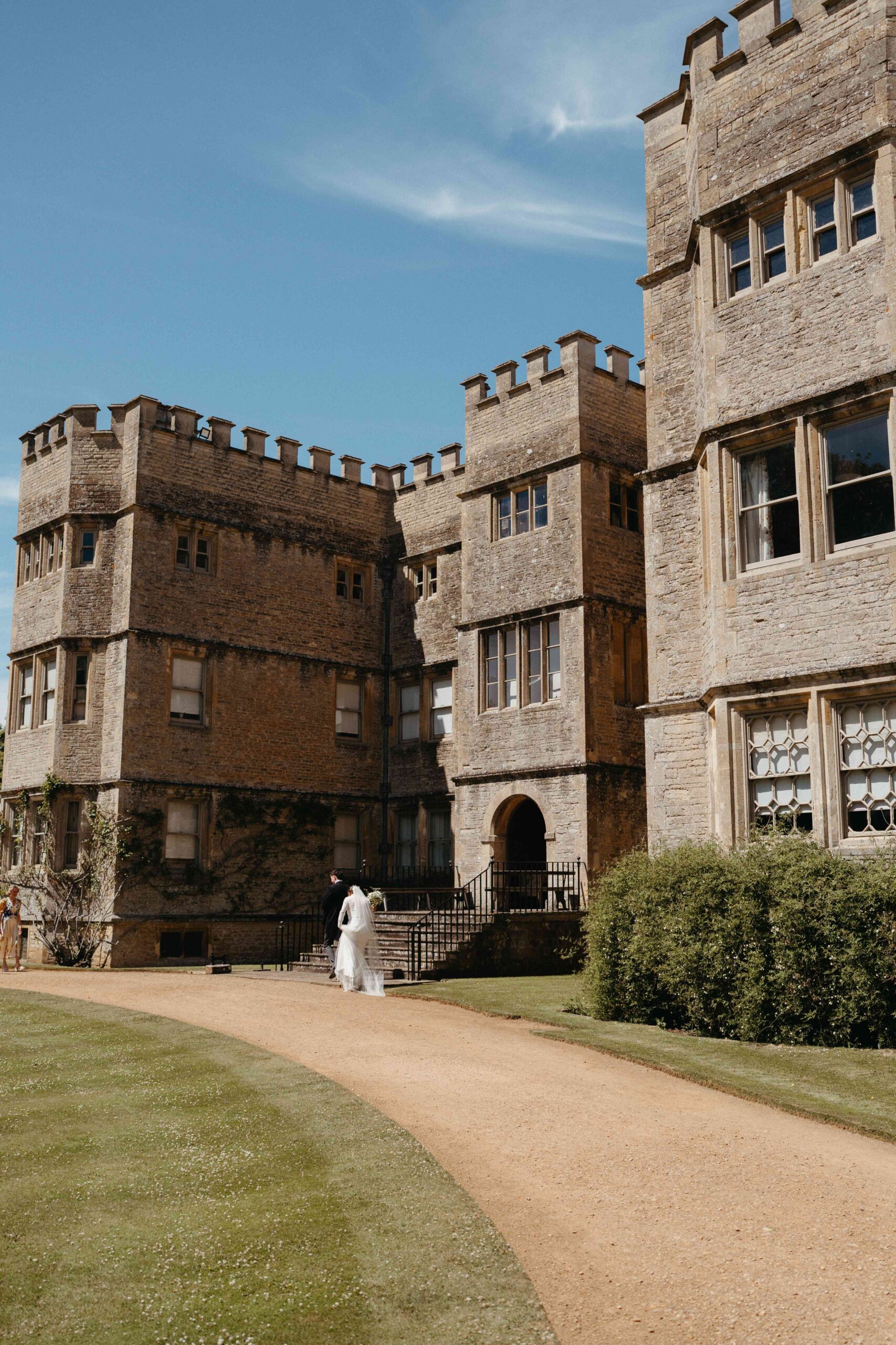 Bride and groom walking up to the historic facade of Rousham House in Oxfordshire
