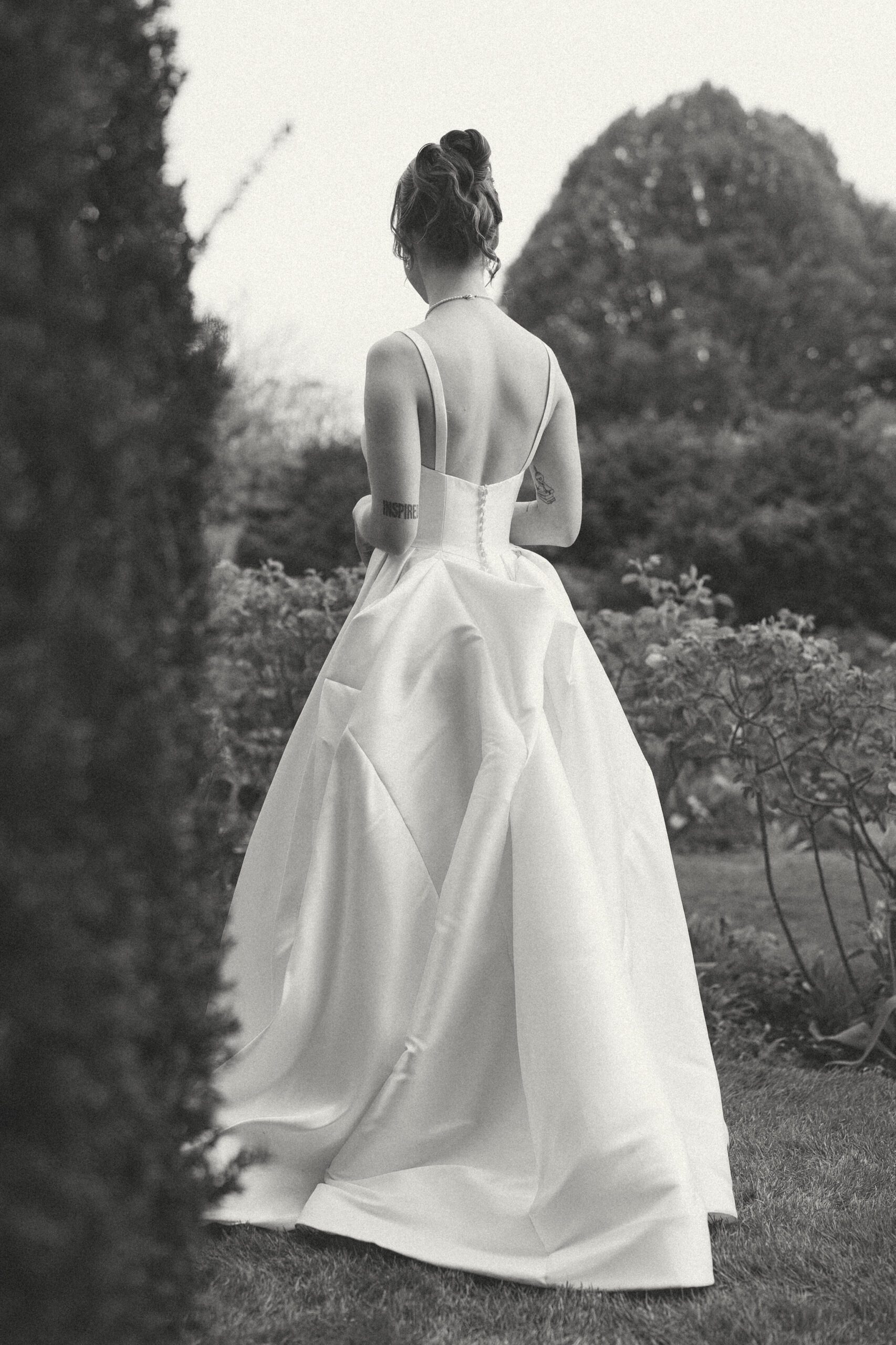 Bride photographed from behind among trees, editorial wedding photography