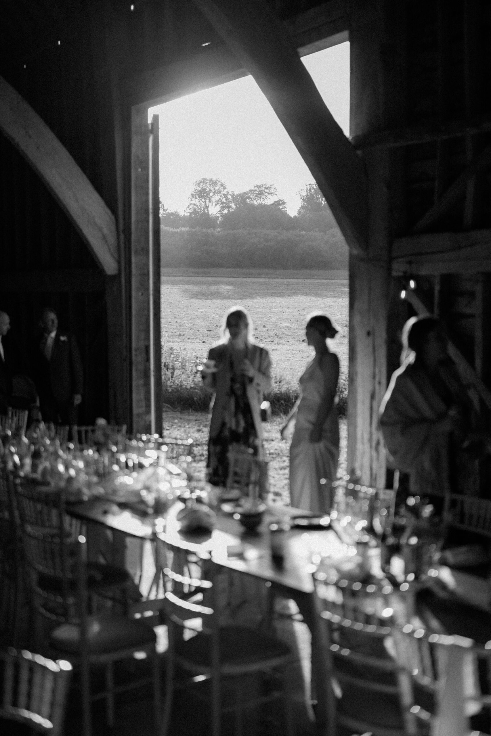 Black and white photograph of guests silhouetted in a barn doorway